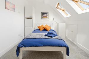 a bedroom with a bed with blue sheets and orange pillows at Sky View En-Suite in Egham
