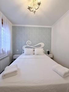 a bedroom with a large white bed with a chandelier at Apartamento Oyón in Logroño