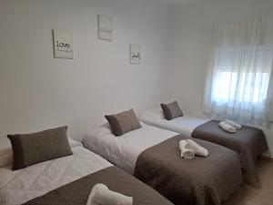 a room with three beds with towels on them at Apartamento Los Angeles Cerca Estación Tren Aeropuerto in Málaga