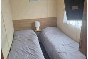 a bedroom with two beds and a table with a lamp at Beautiful 8 Berth - Caravan - Abergele in Abergele