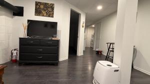 a room with a toilet and a television on a dresser at Velora Stays in Kelowna