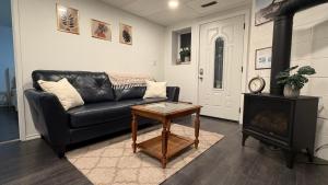 a living room with a black leather couch and a table at Velora Stays in Kelowna