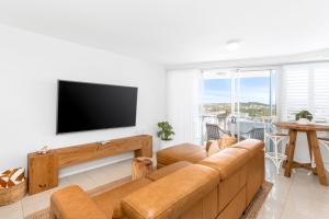 a living room with a couch and a flat screen tv at 'Still & Sea' in Yeppoon's CBD in Yeppoon
