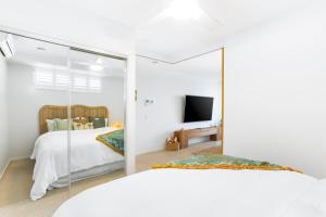 a bedroom with a white bed and a mirror at 'Still & Sea' in Yeppoon's CBD in Yeppoon +6 photos