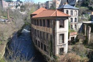 an old building sitting on the side of a river at A côté de la Gare in Thiers +19 photos