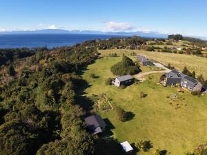 an aerial view of a house on a field with the water at Ave Lodge Frutillar in Frutillar
