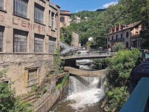 a river in a city with a bridge and buildings at A côté de la Gare in Thiers