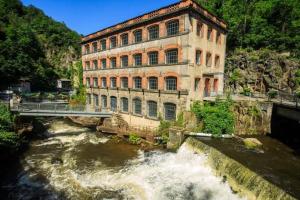 a building next to a river with a bridge at A côté de la Gare in Thiers