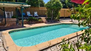 a swimming pool in a yard with two chairs and an umbrella at Cozy studio in medieval town in Le Val