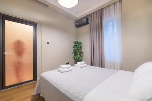 a bedroom with a white bed with towels on it at ICONIC LEGACY Suite seafront in Thessaloniki