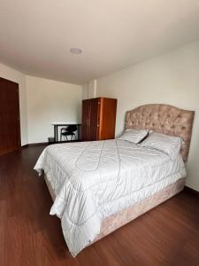 a bedroom with a large bed and a wooden floor at "Wampu" - Amplio apartamento cerca del Centro Histórico in Cuenca