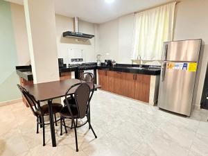 a kitchen with a table and a stainless steel refrigerator at "Wampu" - Amplio apartamento cerca del Centro Histórico in Cuenca