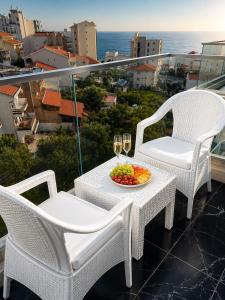a table with two chairs and a bowl of fruit and wine glasses at Becici residance pool and sauna in Bečići