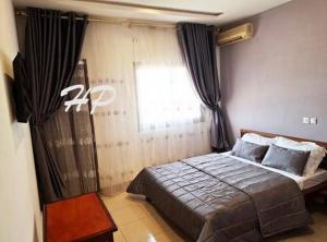 a bedroom with a large bed with a window at Hôtel Les Pyramides in Yaoundé