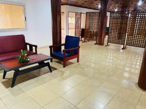 a living room with a couch and a table and chairs at Hôtel Les Pyramides in Yaoundé +1 photo