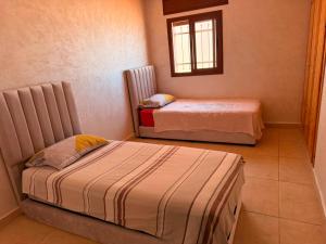 two beds in a small room with a window at Complexe luxury in Oued Laou