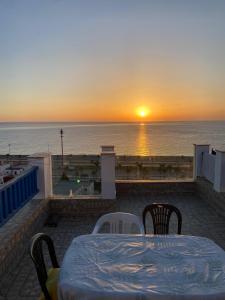 a sunset over the ocean with a table and chairs at Complexe luxury in Oued Laou