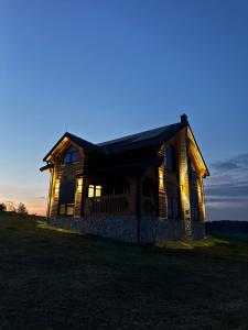 an old house with lights on in a field at Agro Arge in Rožaje