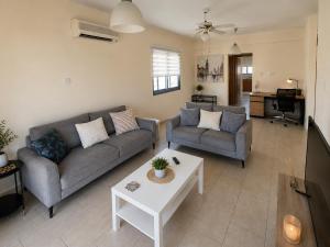 a living room with two couches and a table at Villa Paradise Complex - Pyla Larnaca in Pyla