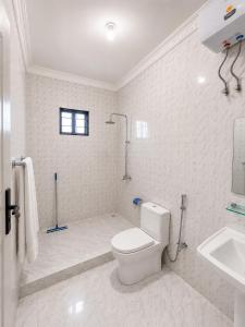 a white bathroom with a toilet and a sink at Nanaa Hotel in Nungwi +11 photos