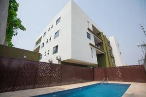 a building with a swimming pool in front of a building at Wentworth - SKYSUITES in Accra