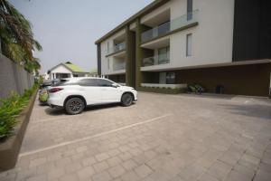 a white car parked in a parking lot in front of a building at Wentworth - SKYSUITES in Accra +10 photos