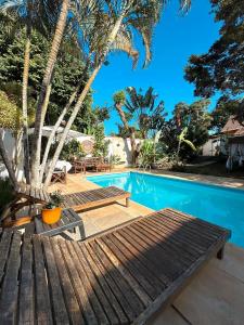 a wooden bench next to a swimming pool with palm trees at Casa Valldemossa in Búzios +40 photos