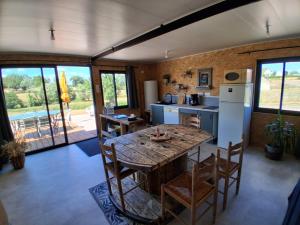 a kitchen with a wooden table with chairs and a refrigerator at Refuge climatisé tout proche du Pal in Le Pin
