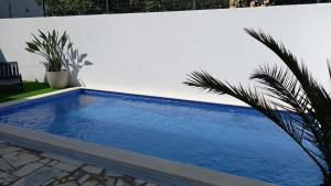 a blue swimming pool next to a white wall at Maison de vacances Casa Rocha in Armação de Pêra
