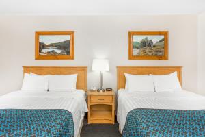 a hotel room with two beds and a night stand at Days Inn by Wyndham Jefferson in Jefferson