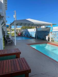 a swimming pool with a table and benches next to it at 2 Pools - Solar - Playa Santa - Apto E in Guanica