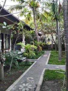 a walkway in front of a house with palm trees at Pondok Aldi Hostel in Amed