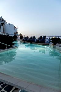 a large swimming pool with lounge chairs in front of the ocean at Sea View Kerame in Evdilos