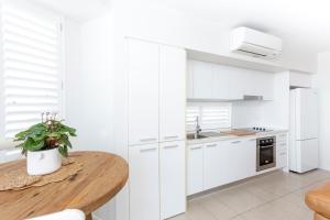 a kitchen with white cabinets and a wooden table at 'Still & Sea' in Yeppoon's CBD in Yeppoon