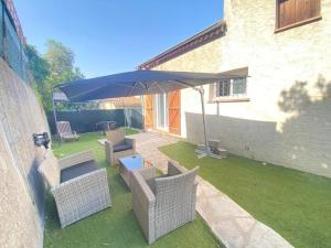 a patio with chairs and an umbrella on the grass at Villa Emeraude in Cagnes-sur-Mer