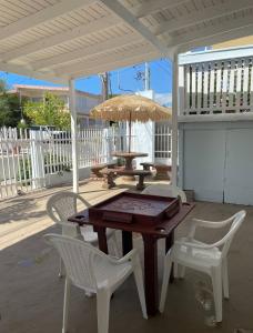 a wooden table and chairs on a patio with an umbrella at Walk to Beach - Pool - Billar - Apto D in Guanica