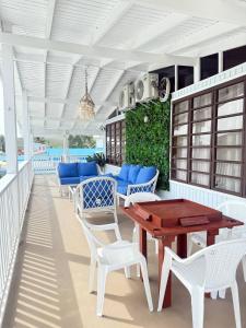 a porch with white chairs and a wooden table at Walk to Beach - Pool - Billar - Apto D in Guanica
