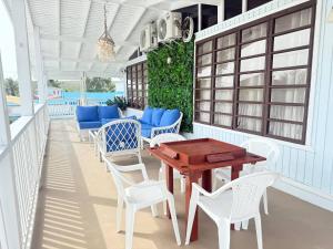 a porch with white chairs and a wooden table at Walk to Beach - Pool - Billar - Apto D in Guanica
