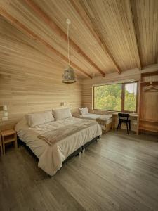 a bedroom with two beds in a room with wooden walls at Ave Lodge Frutillar in Frutillar