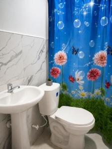 a bathroom with a toilet and a sink and a shower curtain at Brisa y Lienzo - Hostal Boutique in Puerto Colombia
