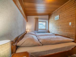 a bed in a room with a wooden wall at Das Bergnest Dorfglück in Söll