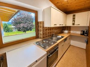 a kitchen with a sink and a large window at Das Bergnest Dorfglück in Söll