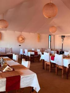 a dining room with tables and chairs and lights at Sahara Nights Luxury Camp in Merzouga