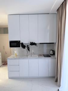 a white kitchen with white cabinets and a sink at Alisa's apartments Ureki in Ureki +24 photos