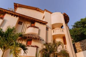 a building with palm trees in front of it at Pacífica Grand Zihuatanejo in Zihuatanejo