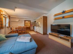a living room with a blue couch and a television at Das Bergnest Bergluft in Söll
