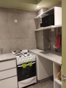 a kitchen with a stove and a microwave at JAZCA Huayco in San Salvador de Jujuy