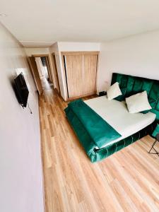 a bed in a room with a green couch at Appartement Cozy avec piscine in Sidi Rahal