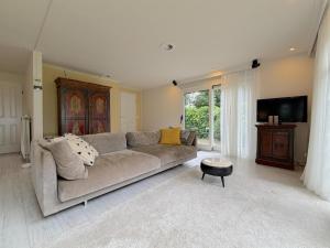 a living room with a couch and a tv at Villaatje Veluwe in Garderen