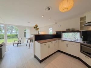 a kitchen with white cabinets and a dining room with a table at Villaatje Veluwe in Garderen